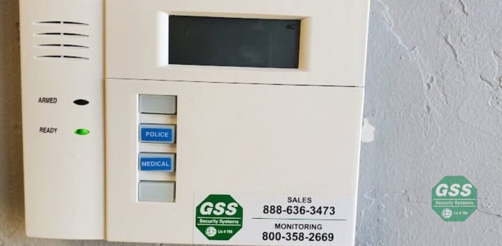 A burglar alarm keypad with a red light indicating it is armed,