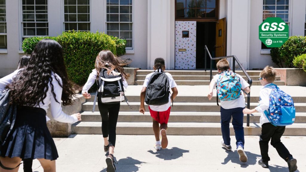 A group of children wearing backpacks excitedly running up the steps of a school building, ready for a new school day.